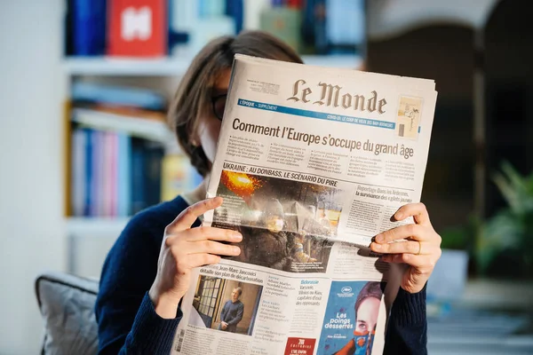 Mujer leyendo el periódico francés Le Monde con portada principal Ucrania: en Donbass el peor escenario antes de la invasión de Rusia —  Fotos de Stock