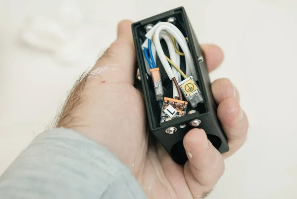 POV electrician male hand holding lamp luminaire component with splicing connectors — Stock Photo, Image