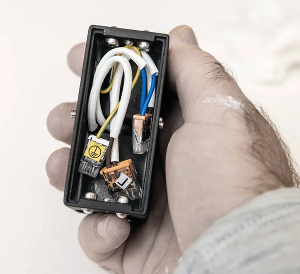 POV electrician male hand holding lamp luminaire component with splicing connectors — Stock Photo, Image