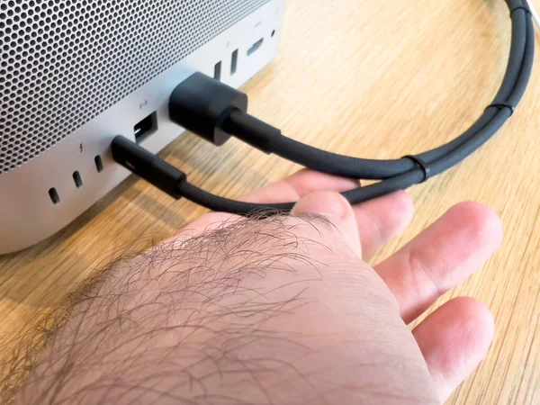 POV mužská ruka drží splétaný kabel z nových Apple Computers Mac Studio M1 Ultra s connectio — Stock fotografie