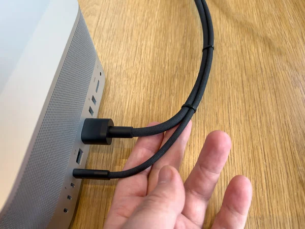 POV male hand holding braided cable of new Apple Computers Mac Studio M1 Ultra with connectio — Stock Photo, Image
