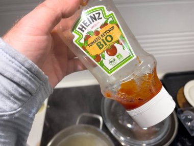Erkek el, Heinz Domates Biyolojisi ketçaplı neredeyse boş bir şişe tutuyor.