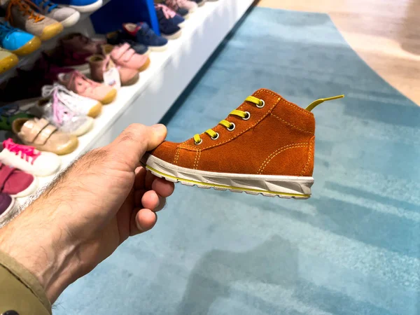 POV mano masculina sosteniendo la compra de zapatos pequeños niños azules — Foto de Stock