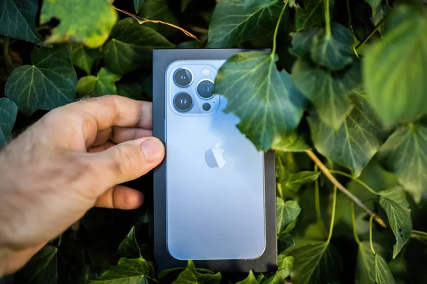 POV mannelijke hand-holding in groene tuin tussen bladeren pakket doos van nieuwe iPhone 13 Pro — Stockfoto