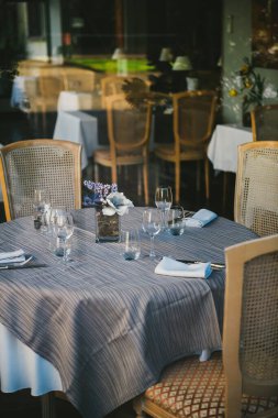 Bardaklar, peçeteler, çiçekler, çatal, bıçak, hepsi restoranda yemek servisine hazır..