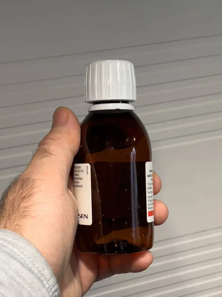 POV mano masculina sosteniendo contra botella de fondo blanco con Izinova una preparación salina a base de sulfato para la limpieza intestinal indicada antes de cualquier procedimiento que requiera un intestino limpio — Foto de Stock