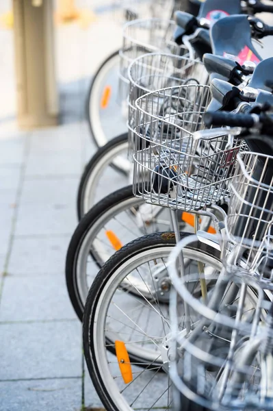 Общественный прокат велосипедов в центре города с рядами чистых алюминиевых городских велосипедов с корзинами — стоковое фото