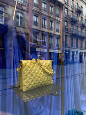 Altın sarısı Louis Vuitton kadın çantasının sunumu. Fransız şehrinin dekoratif vitrininde tramvay yansımalarıyla sunuluyor.