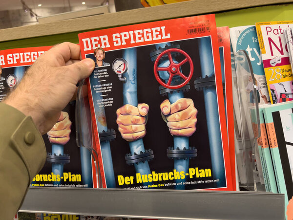 POV male hand holding in newspaper kiosk latest edition of the Der Spiegel German magazine with the title The Escape paln from Gazprom