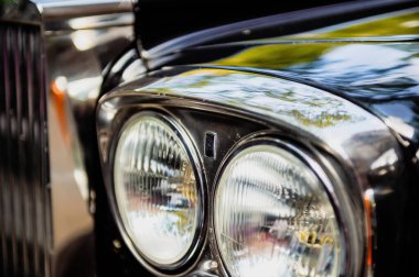 Şehre park etmiş lüks Rolls-Royce araba limuzininin ön görüntüsü - aralarında logo bulunan cam farların yakın çekimi