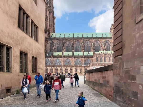 Grupp av turister går på den gamla kullerstensgatan med majestätiska Notre-Dame de Strasbourg katedralen i bakgrunden — Stockfoto