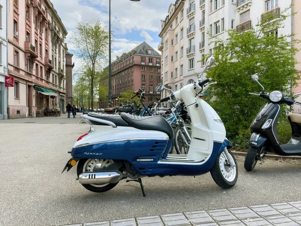 Arka planda Fransa 'nın Strazburg kenti Peugeot Motosikletli yeni beyaz Scooter Django Standard 125' in yan görüntüsü