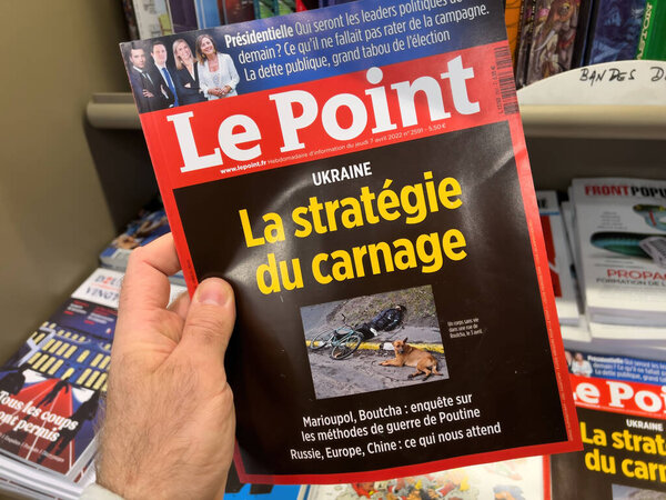 Мужчина покупает в газетном киоске Le Point международный газетный журнал с мертвым человеком на улицах Украины