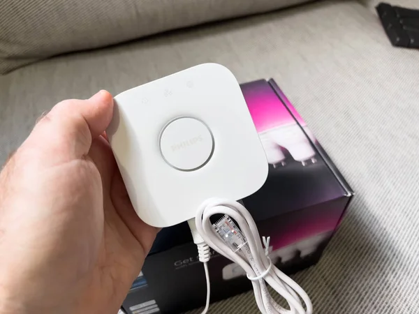 POV male hand holding new Philips Hue bridge above cardboard box - — стоковое фото