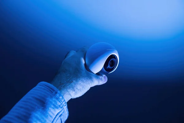 Maschio mano tenendo moderna piccola telecamera di sorveglianza 8k UHD con il ciclope come obiettivo — Foto Stock