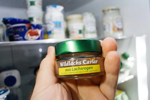 POV mano masculina sosteniendo vidrio pequeño recipiente con Wildlachs Caviar aus Lachsrogen — Foto de Stock