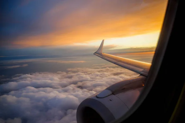 Airplane wing above clouds with divine sunset sunrise — Stockfoto