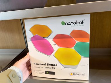 POV of male hand holding package of Nanoleaf led lights hexagons starter kit at the Apple Inc. flagship store - with HomeKit ready sticker