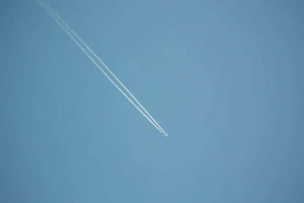 Plane on blue sky with large tail contrail behind - travel at high altitude — Zdjęcie stockowe
