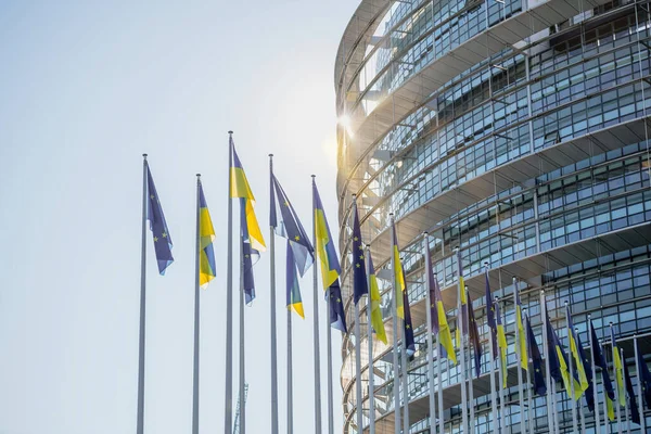 Sunlight flare over the Ukrainian flag flies next to the Flag of Europe and all EU union members flags — Foto de Stock