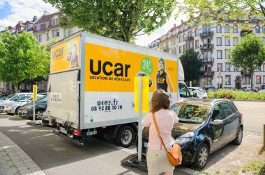 Strasbourg, Fransa - 27 Haziran 2015: Bir apartmanın taşınması sırasında UCAR kargo aracının yanında yürüyen Fransız kadının dikiz görüntüsü - sokakta özel olarak belirlenmiş reklam panoları