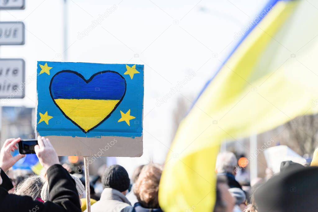 white blue heart has the colors of Ukrainian flag drawn on a placard at general protest against the attack of Russia in Ukraine