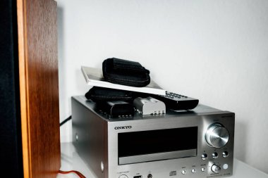 Paris, France - Jan 14, 2015: Onkyo CR-N755 Silver with multiple remote controls and camera photo batteries on the top silver body of Compact Disc Receiver