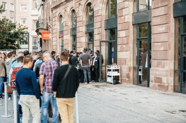 STRASBOURG, FRANCE - SEP, 19 2014: Rear view of group of young people in line queue in front of Apple Store with customers waiting in line to buy the latest iPhone iPad Apple Watch and notebook