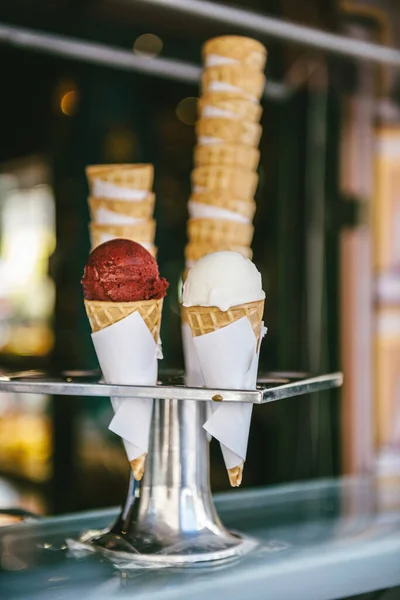 Summer offer ice cream cones in metal hygienic holder on counter at store one red scoop of strawberry ice cream and another white yoghurt one