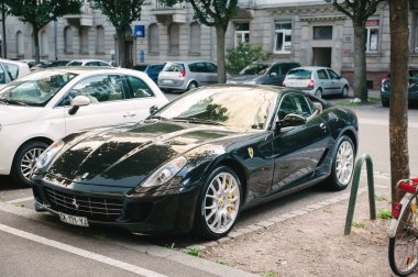 France - Jun 27, 2015: Luxury black ferrari sport car parked in city center with multiple cars parked nearby