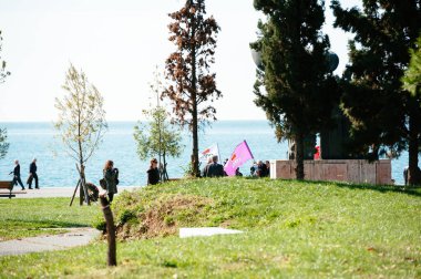 Thessaloniki, Greece - Oct 30, 2014: People with flags protesting in 30th of October Park with Aegean sea in background