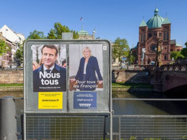 Strasbourg, France - Apr 16, 2022: Emmanuel Macron and marine le Pen election posters on dedicated advertising board with Church cathedral in background