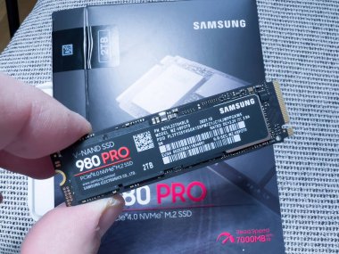 Paris, France - Aug 8, 2022: POV male hand unboxing new Samsung 980 Pro NVME ssd hard disk drive for the personal computer or mac Apple upgrade - 2tb disk on fabric background
