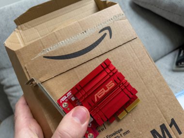 Paris, France - Jan 27, 2022: POV male hand unboxing unpacking Amazon box with new 10GbE Gigabit Ethernet card manufactured by Asus computers - new powerful data internet transmission