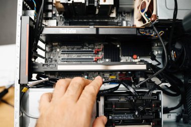 London, United Kingdom - Aug 5, 2022: POV male hand preparing to extract replance the new powerful Nvidia RTX A4000 gpu video card inside powerful workstaiton by Lenovo Thinkstation