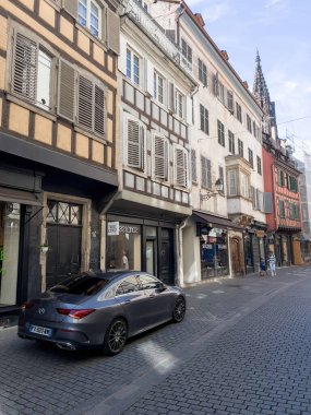 Strasbourg, France - June 25, 2022: New luxury Mercedes-Benz sports car parked in city center near Free lance clothes store shop with Notre-Dame de Strasbourg cathedral in background