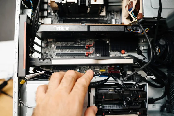 London, United Kingdom - Aug 5, 2022: POV male hand preparing to extract replance the new powerful Nvidia RTX A4000 gpu video card inside powerful workstaiton by Lenovo Thinkstation