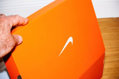Hilversum, Netherlands - May 5, 2022: POV male hand holding red package of Nike running show with the iconic swosh logo