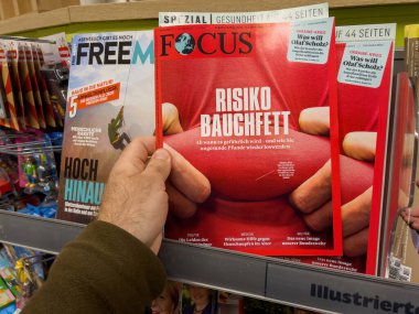 Berlin, Germany - Apr 23, 2022: Focus German magazine newspaper in male hand at press kiosk with Belly fat risk headline and illustrative photograph