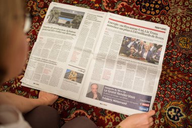 Paris, Fransa - 9 Eylül 2022: POV 'lu kadın oturma odası halısında Fransız iş gazetesinde Liz Truss' un 2300 doların altındaki enerji faturalarını tutmak için 150 milyar dolar ayırdığı yazısını okuyor.