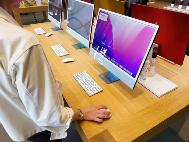 Paris, Fransa - 9 Eylül 2022: M1 çipli en son MAC kişisel bilgisayarına bakan kadının yan görüntüsü - MacO 'ların nasıl çalıştığını anlamaya çalışıyor