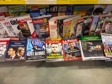 Paris, Fransa - 17 Nisan 2022: POV erkek eli basın büfesinin içinde LExpress, LObs, Valeurs, Le Point, Gaston dergilerinin Emmanuel Macron adaylarının yer aldığı son sayısı