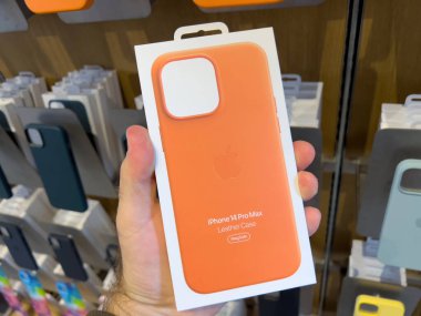 Paris, Fransa - 16 Şubat 2022: POV erkek el ele tutuşması paketi Apple Store 'da yeni turuncu iPhone 14 Pro Max deri çanta ile MagSafe şarj ediliyor