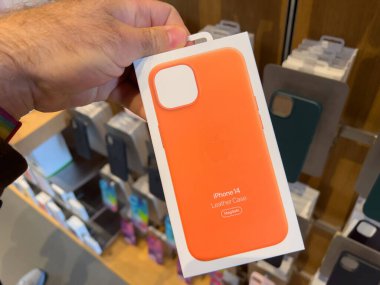 Paris, Fransa - 16 Sep 2022: Apple Store 'da yeni turuncu iPhone 14 deri çantalı ve şarj olan POV erkek el ele tutuşma paketi