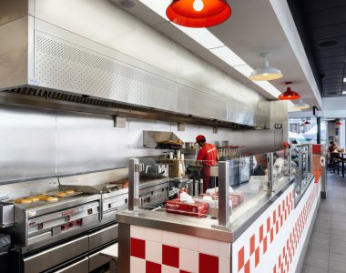 Paris, Fransa - 21 Eylül 2022: Hamburger, sosisli ve patates kızartması odaklı Five Guys Amerikan fast food zincirinin içinde patates kızartması hazırlayan genç işçi