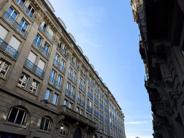 Low angle view of luxury French haussmannian apartment building with clear blue sky above the street