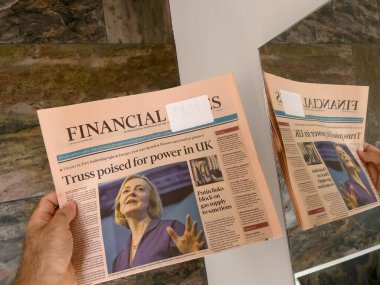 Londra, Birleşik Krallık - 6 Şubat 2022: Birleşik Krallık 'ın yeni başbakanı Liz Truss' un yer aldığı Financial Times gazetesini okuyan erkek el ele tutuşması aynada yansıma