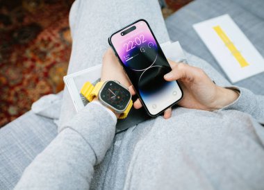 Londra, İngiltere - Bölüm 28, 2022: POV 'lu kadın yeni iPhone 14 Pro' yu elinde tutuyor ve bileğinde yeni Apple Watch serisi Ultra var.