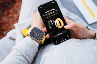 Londra, İngiltere - Bölüm 28, 2022: POV 'lu kadın yeni iPhone 14 Pro' yu elinde tutuyor ve bileğinde yeni Apple Watch serisi Ultra var - telefon durig eşleşmesinde iyi akşamlar mesajı