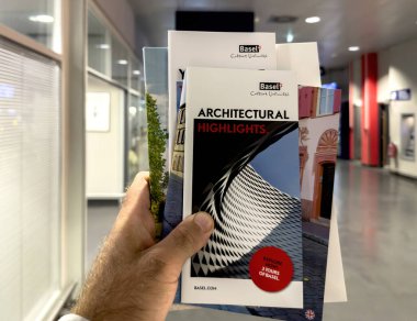 Basel, İsviçre - 22 Eylül 2022: POV erkek, Basel 'in hedefli birden fazla reklam turist bilgilendirme broşürünü elinde tutuyor - havaalanı içi